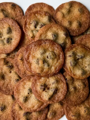 a stack of the Crispiest Chocolate Chip Cookies on a white plate