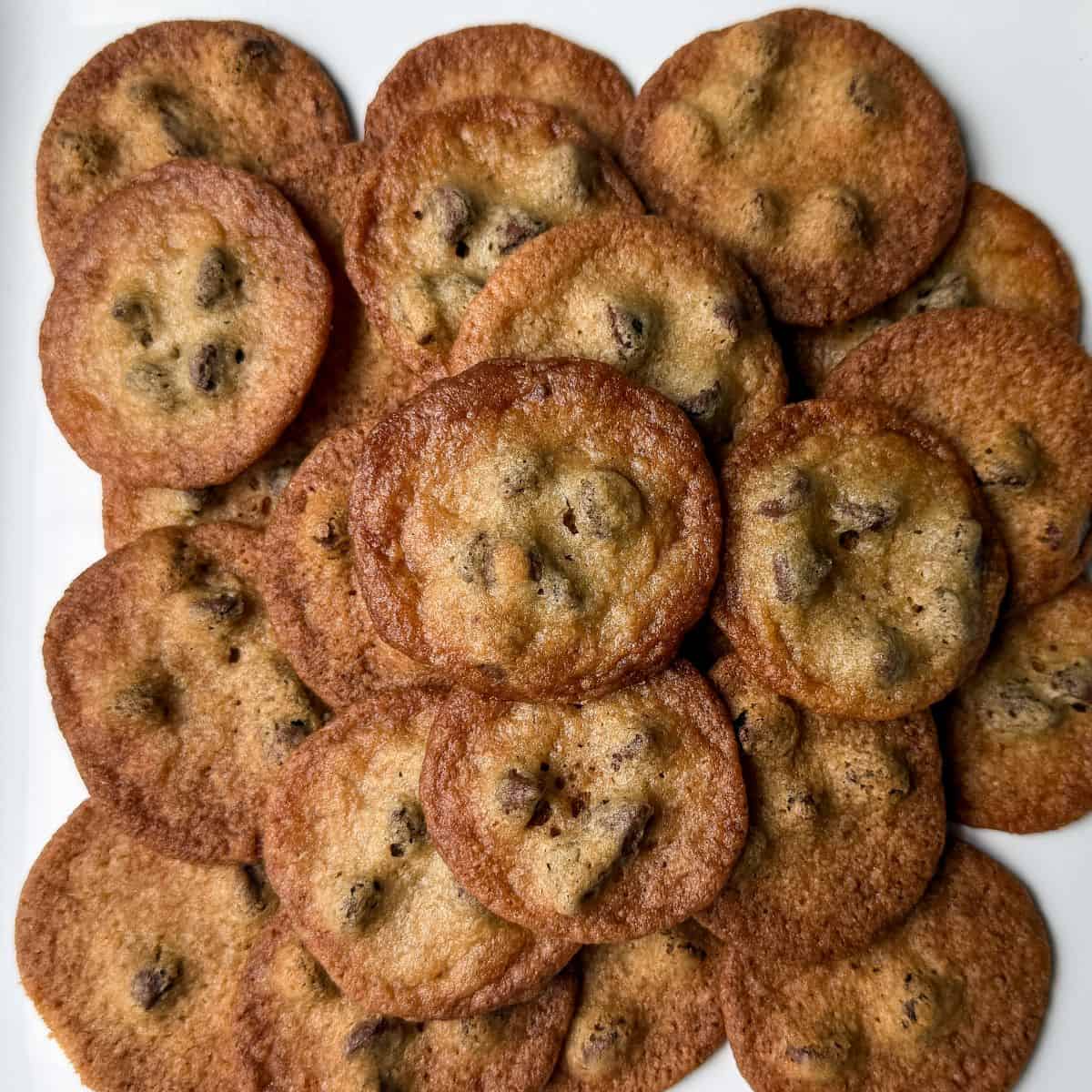 a stack of the Crispiest Chocolate Chip Cookies on a white plate