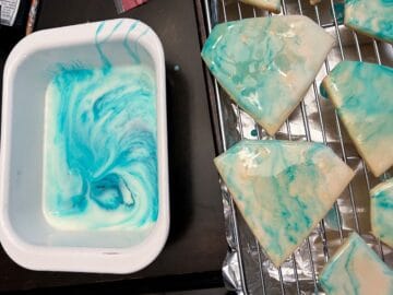 diamond cookies being dipped in blue marbled cookie glaze