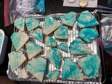 diamond cookies glazed with blue marbled color on a wire rack