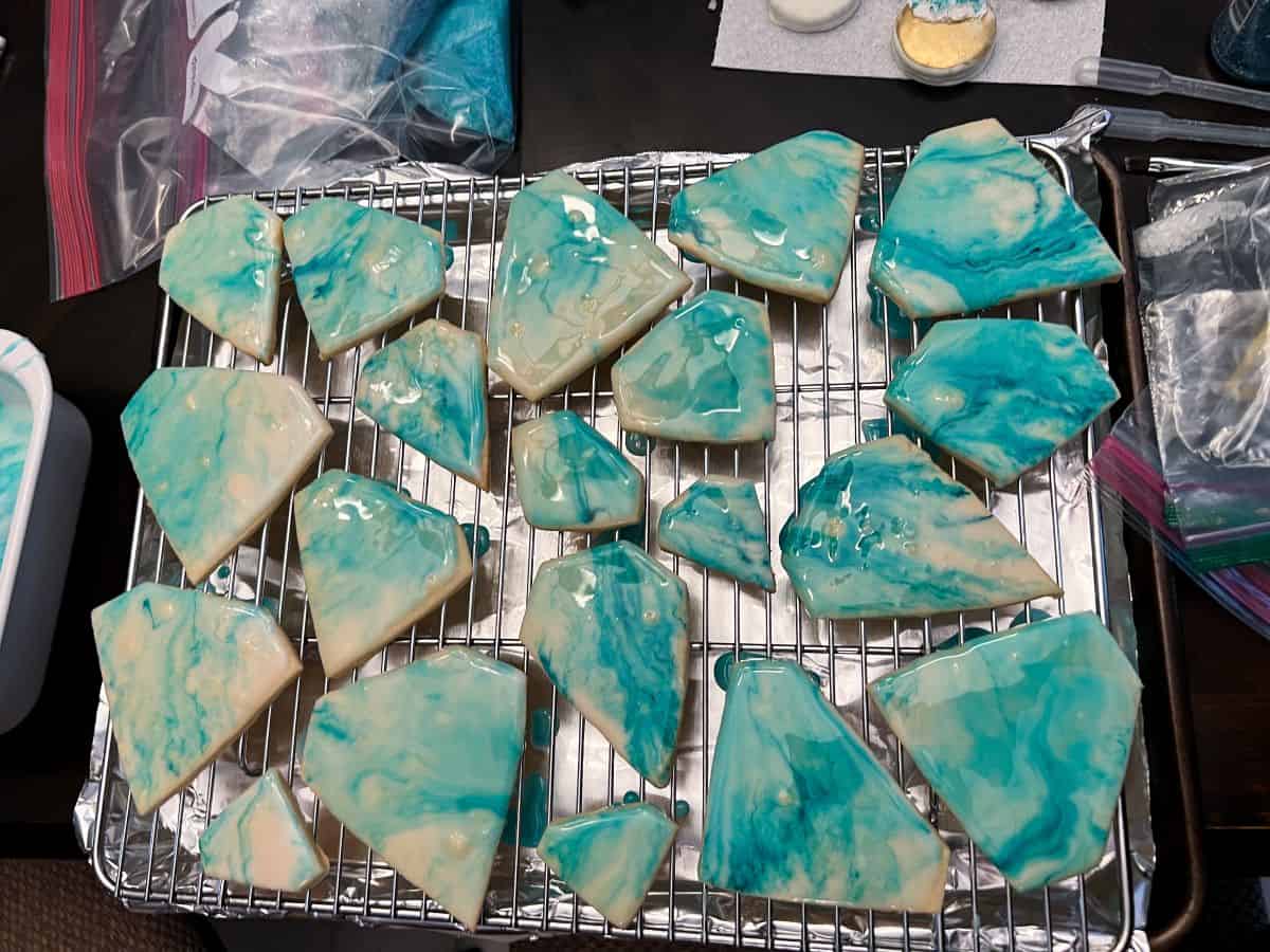 diamond cookies glazed with blue marbled color on a wire rack
