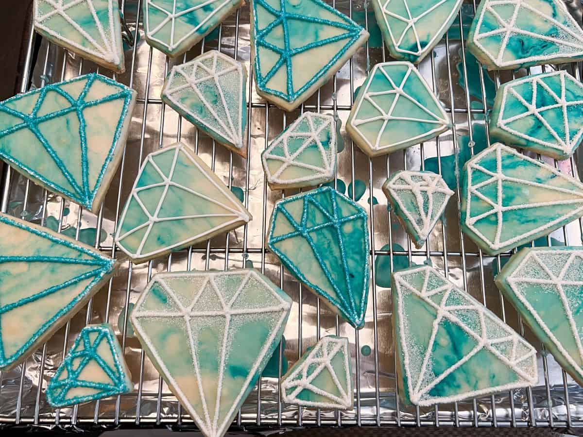 diamond cookies glazed with blue marbled color and piped with royal icing details