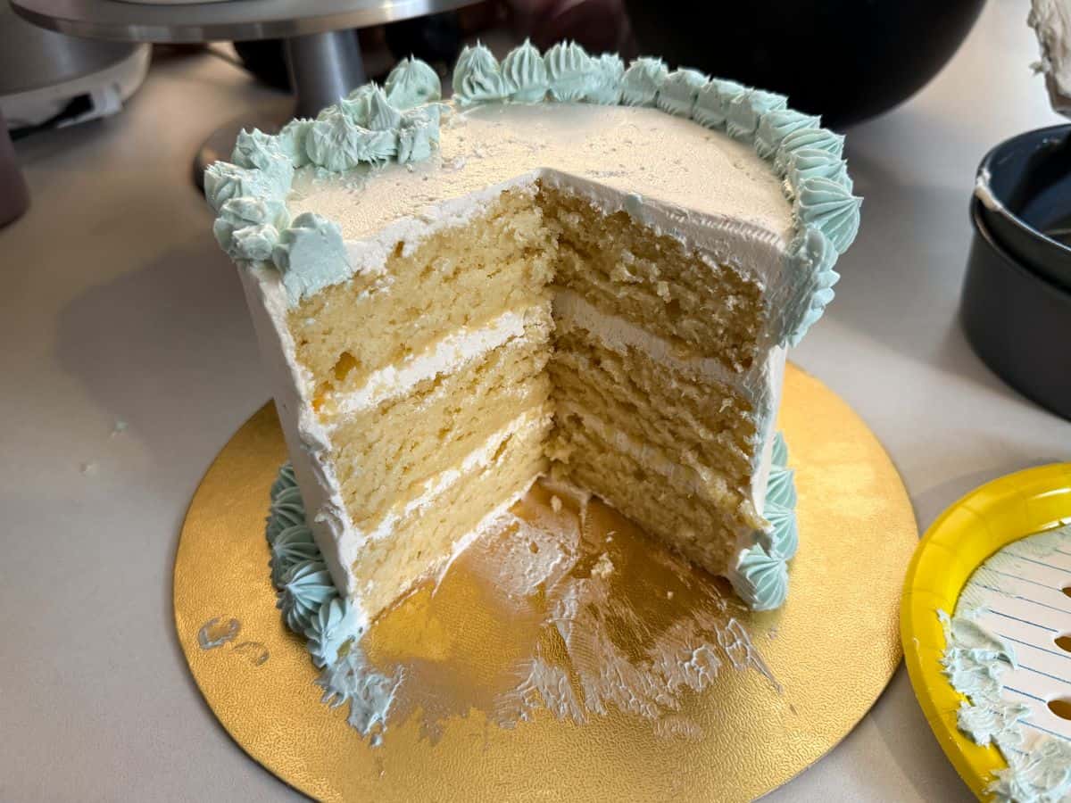 a cut First Day of School Cake to reveal 3 vanilla cake layers with vanilla buttercream between the cakes