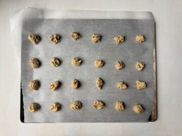small mounds of chocolate chip cookie dough on a parchment paper lined cookie sheet