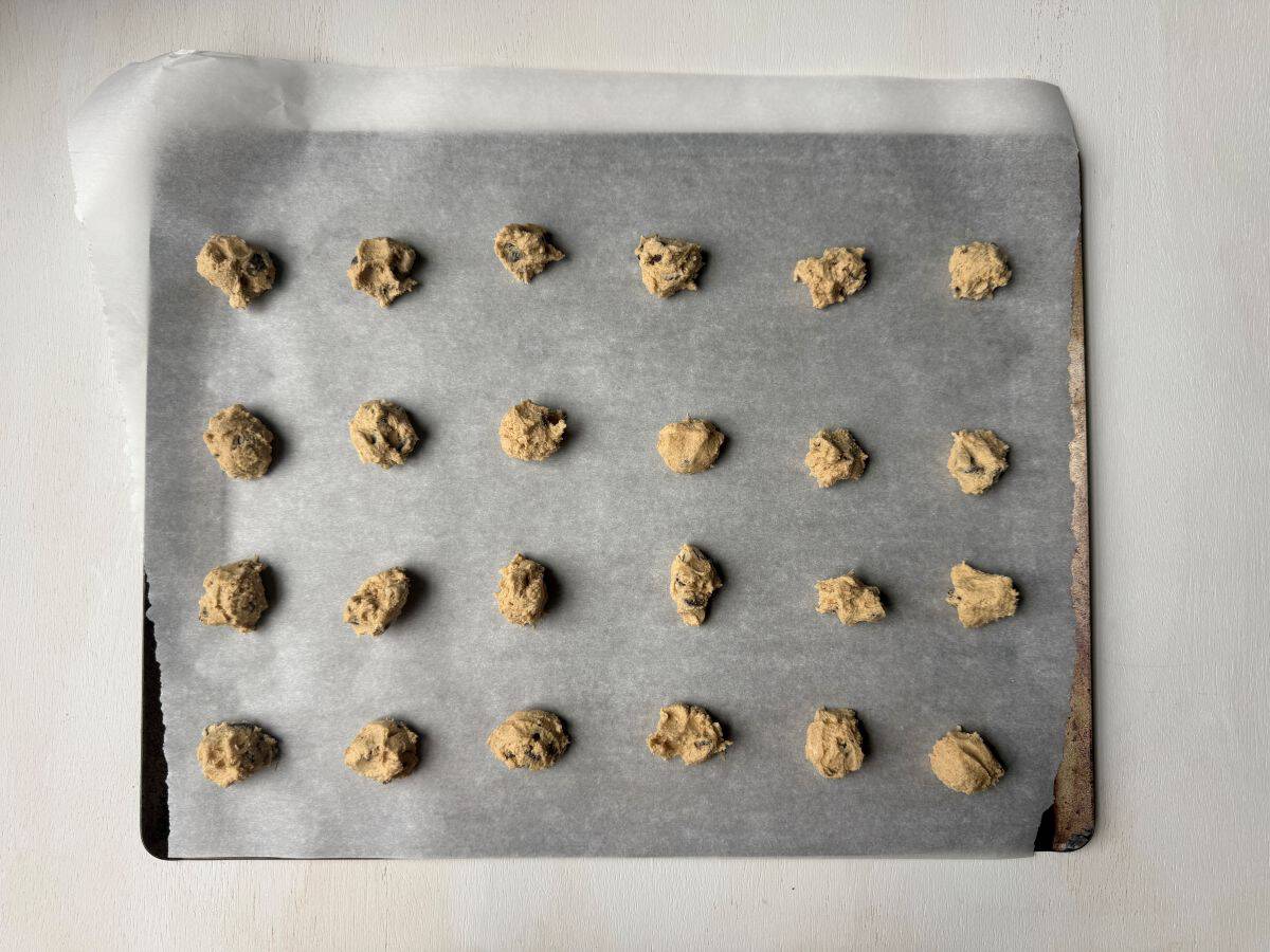 small mounds of chocolate chip cookie dough on a parchment paper lined cookie sheet
