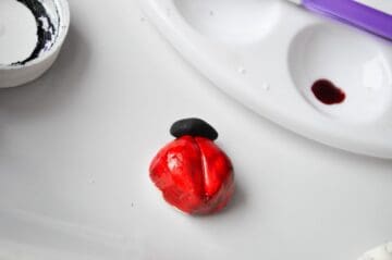 a red painted fondant ladybug with a black fondant head