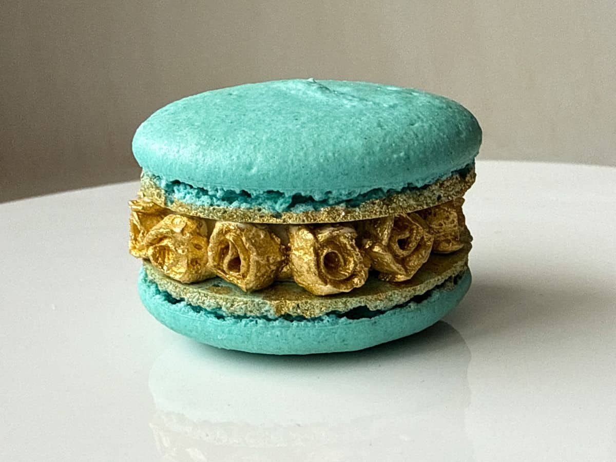 a blue macaron filled with gold buttercream roses