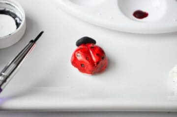 a red painted fondant ladybug with little black spots