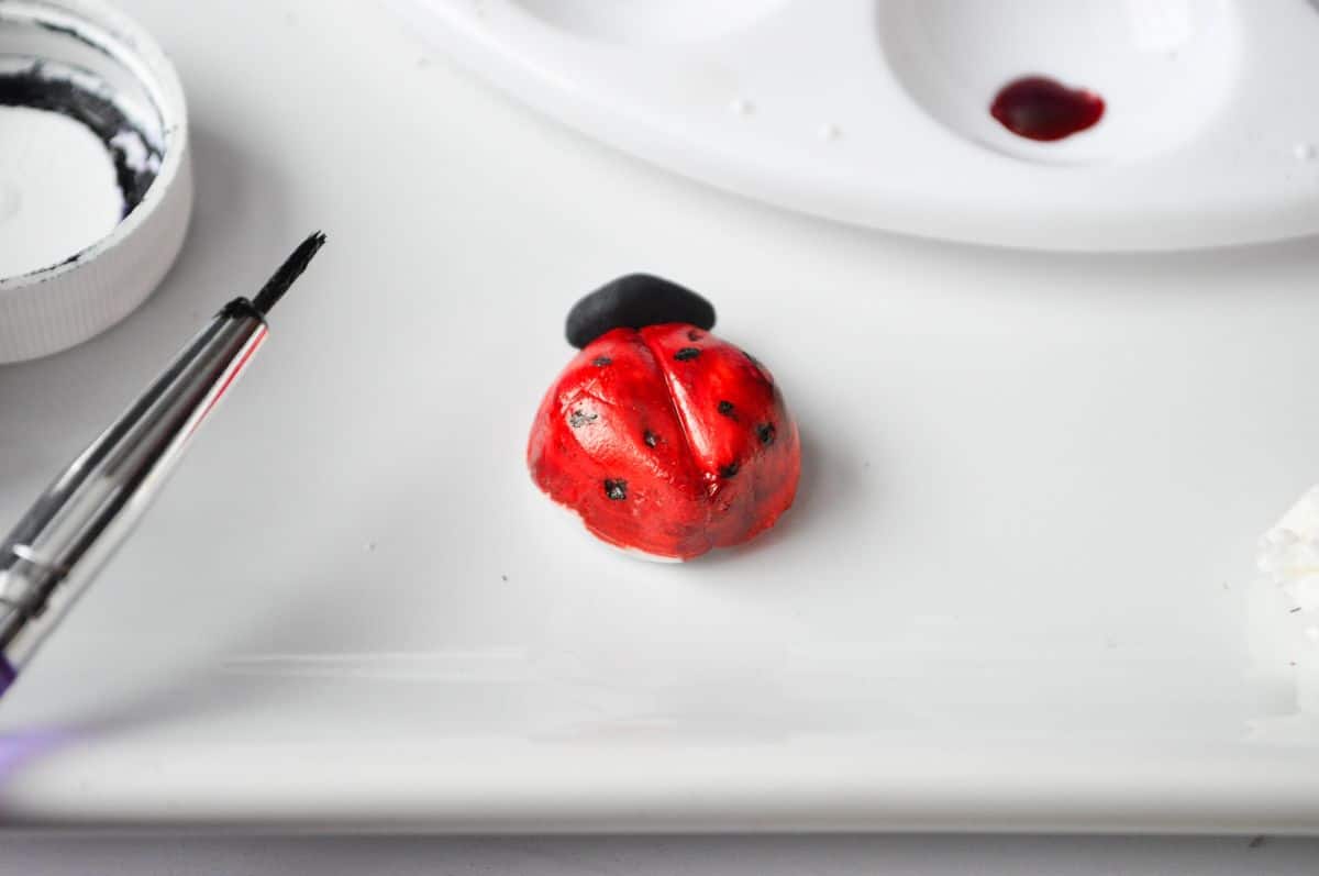a red painted fondant ladybug with little black spots