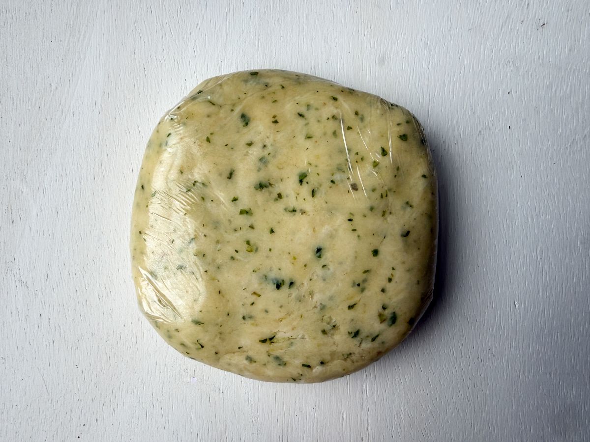 a disk of basil garlic tart dough wrapped in plastic wrap