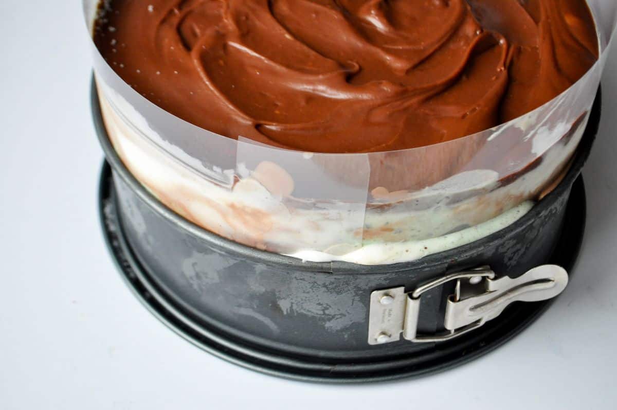 hot fudge on top of ice cream in a springform pan with a clear acetate collar