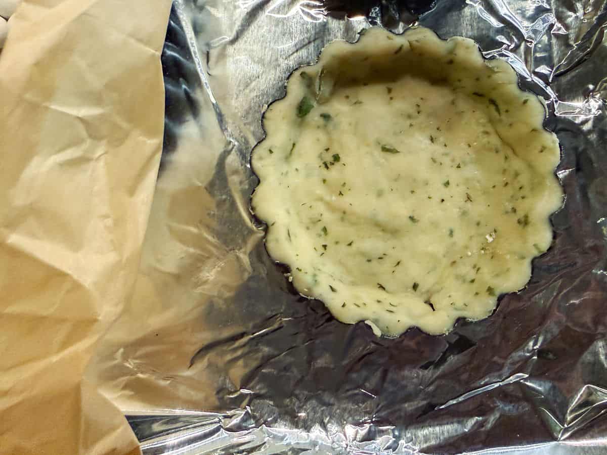 garlic basil dough in a tartlet pan before baking