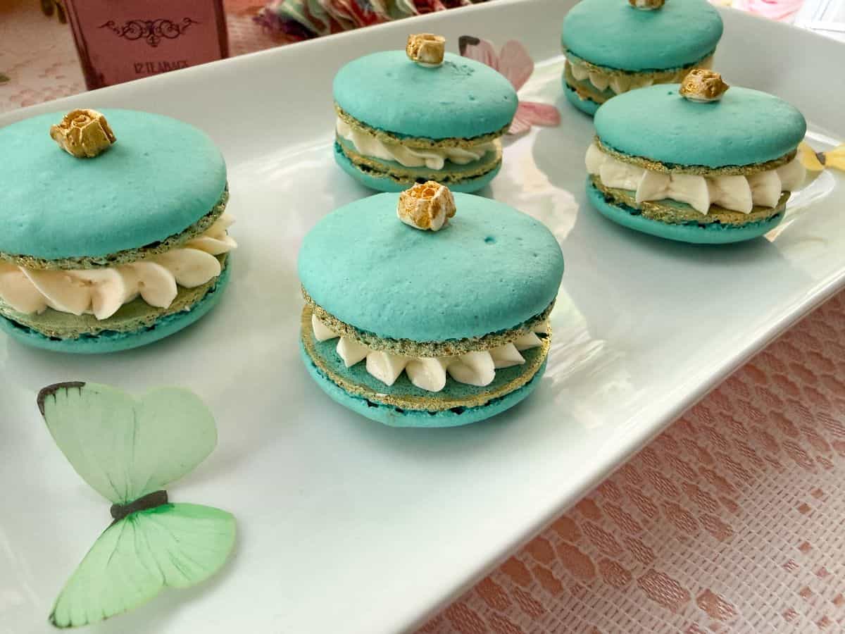 a teal macaron with a gold rose on top