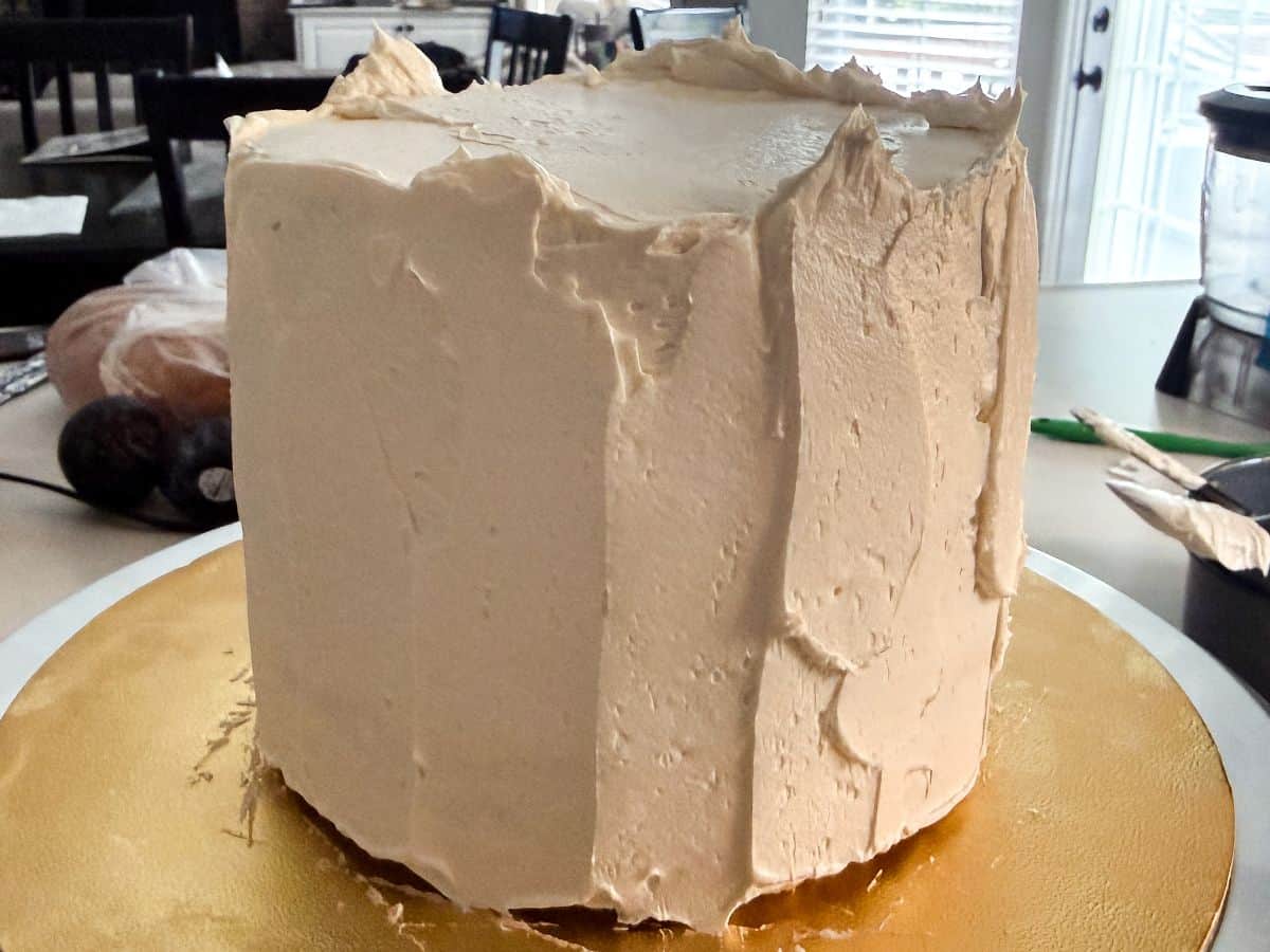 vanilla buttercream covering a 6-inch 3 layer cake before being scraped