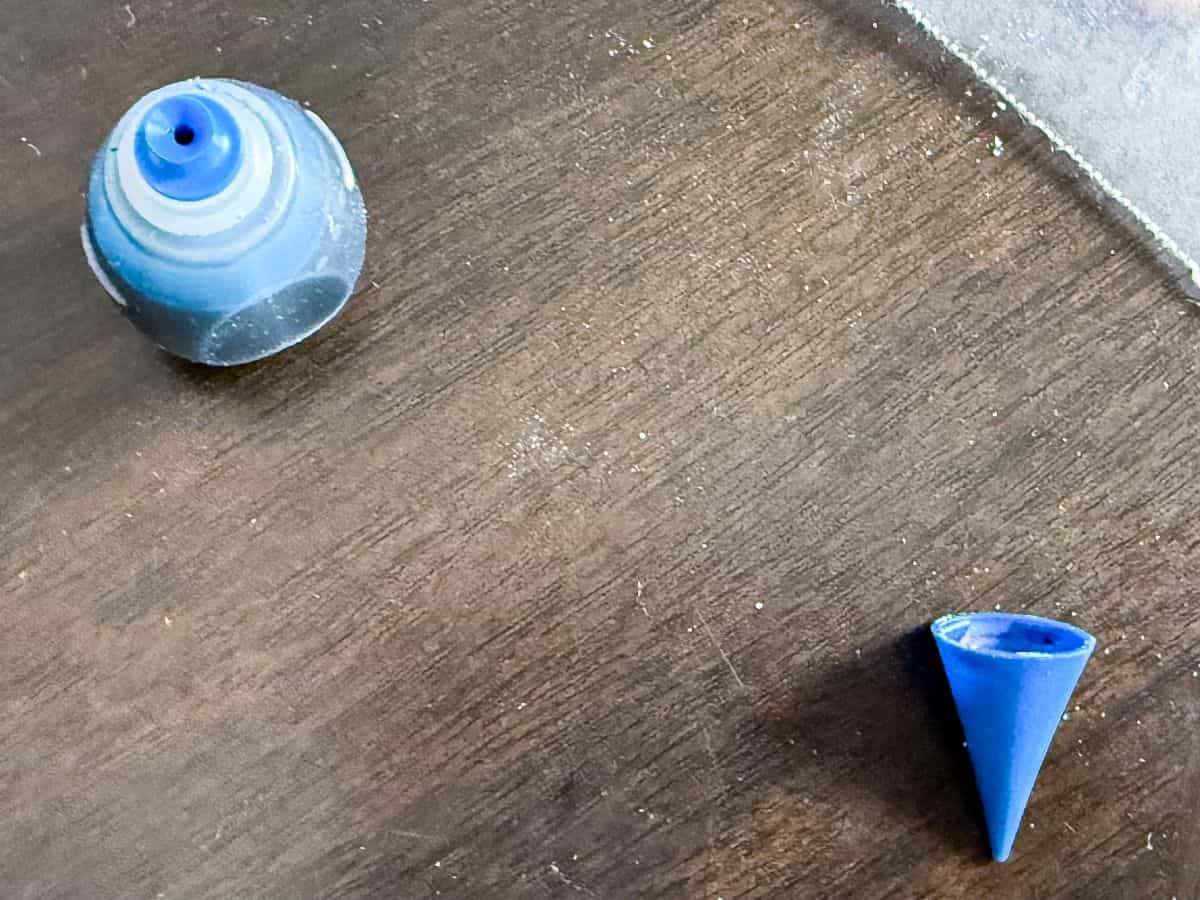 an open bottle of blue food coloring with the cap next to it