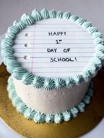 a First Day of School Cake that has a white fondant that looks like notebook paper on top
