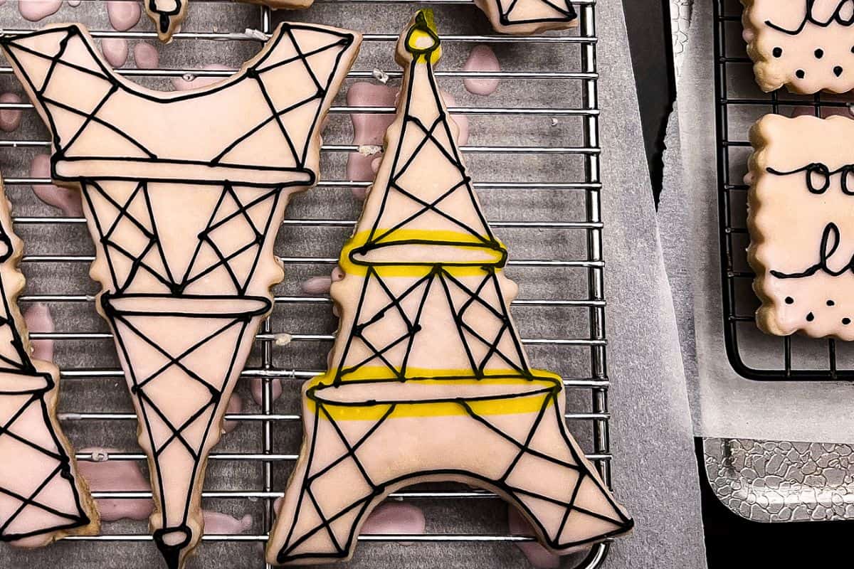 Eiffel Tower cookies with black royal icing details and yellow highlighter to show the first step