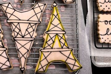 Eiffel Tower cookies with black royal icing details and yellow highlighter to show the second step