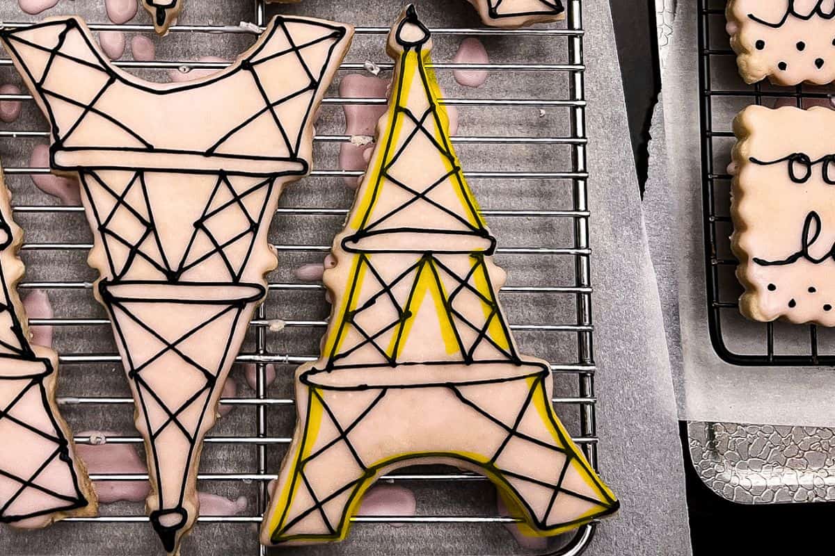 Eiffel Tower cookies with black royal icing details and yellow highlighter to show the second step