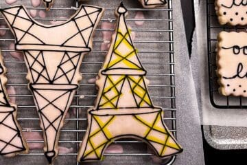 Eiffel Tower cookies with black royal icing details and yellow highlighter to show the third step