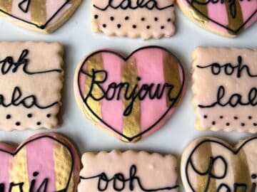 Parisian cookies on a white plate with the center cookie saying "Bonjour"