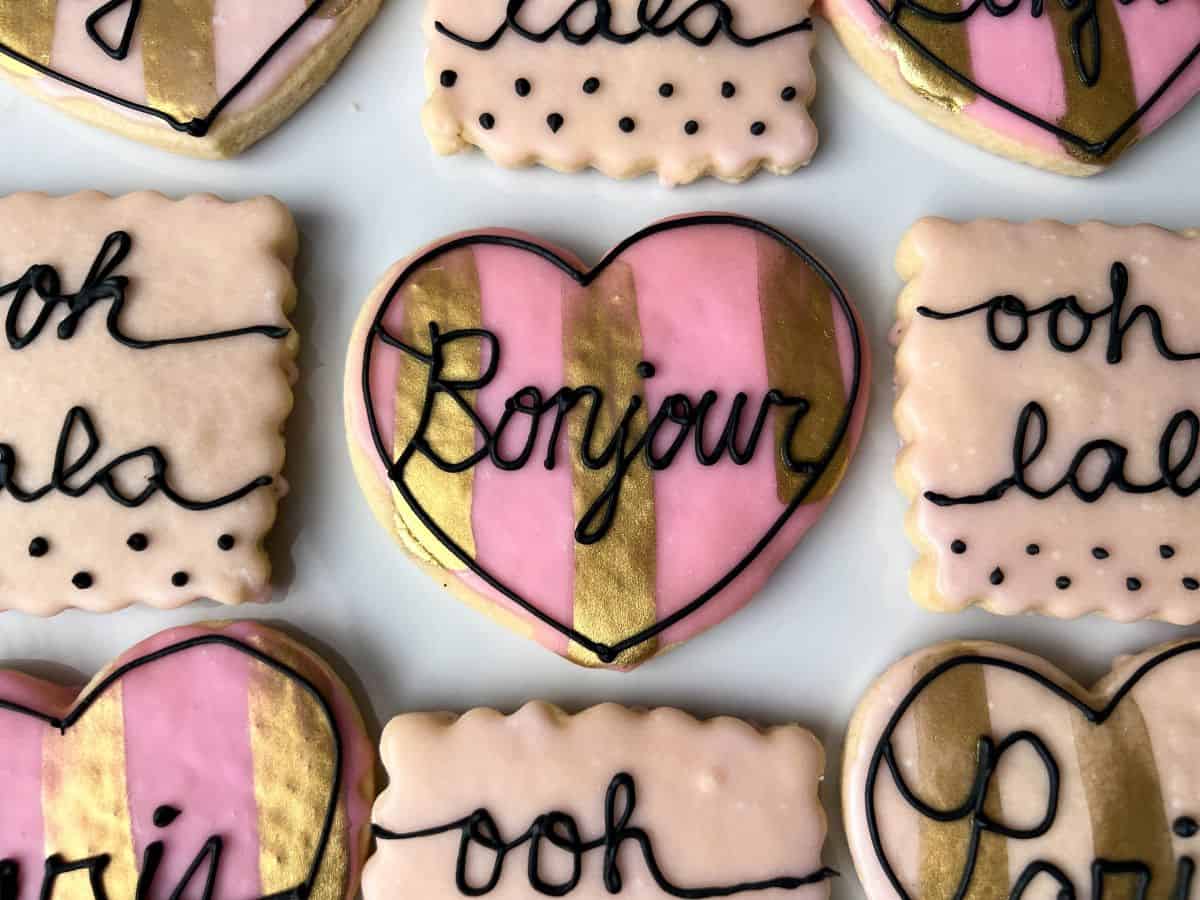 Parisian cookies on a white plate with the center cookie saying "Bonjour"