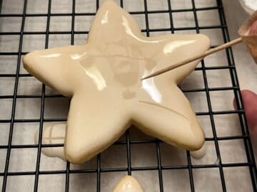 a toothpick popping bubbles in icing on a star shaped cookie
