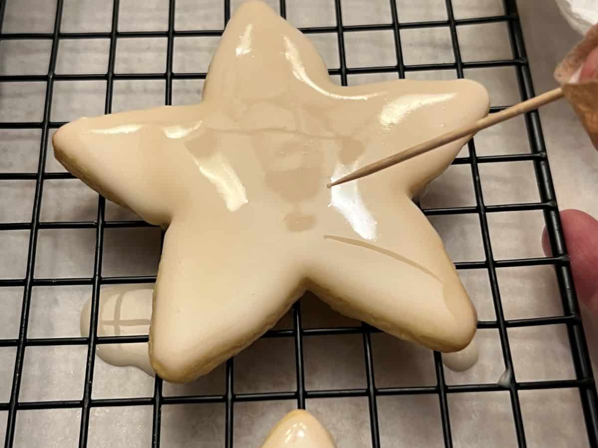 a toothpick popping bubbles in icing on a star shaped cookie