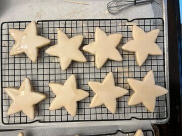 8 iced star cookies drying on a cooling rack