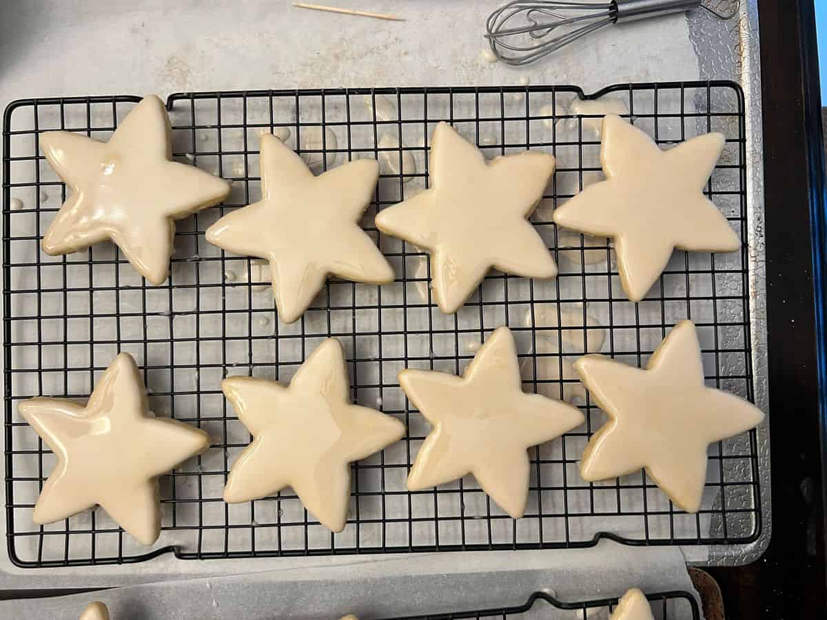 8 iced star cookies drying on a cooling rack 